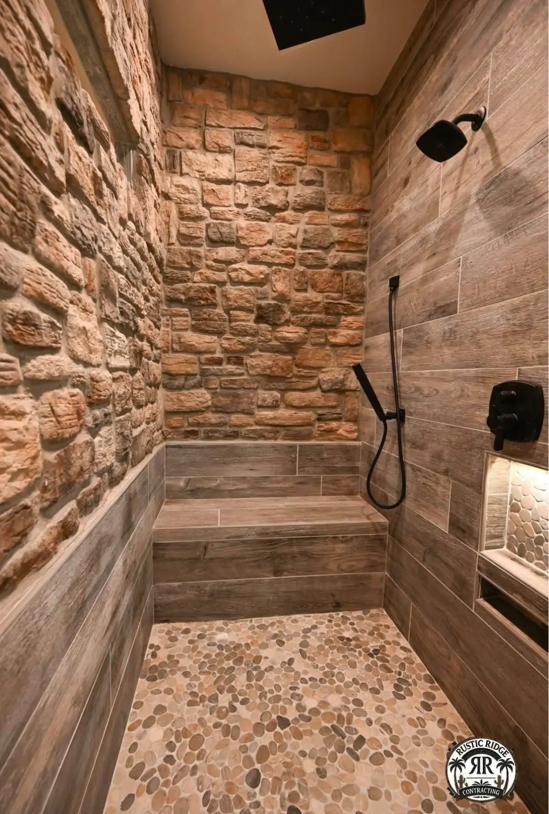 Stone accent wall shower with wood-look tile, built-in bench and pebble floor