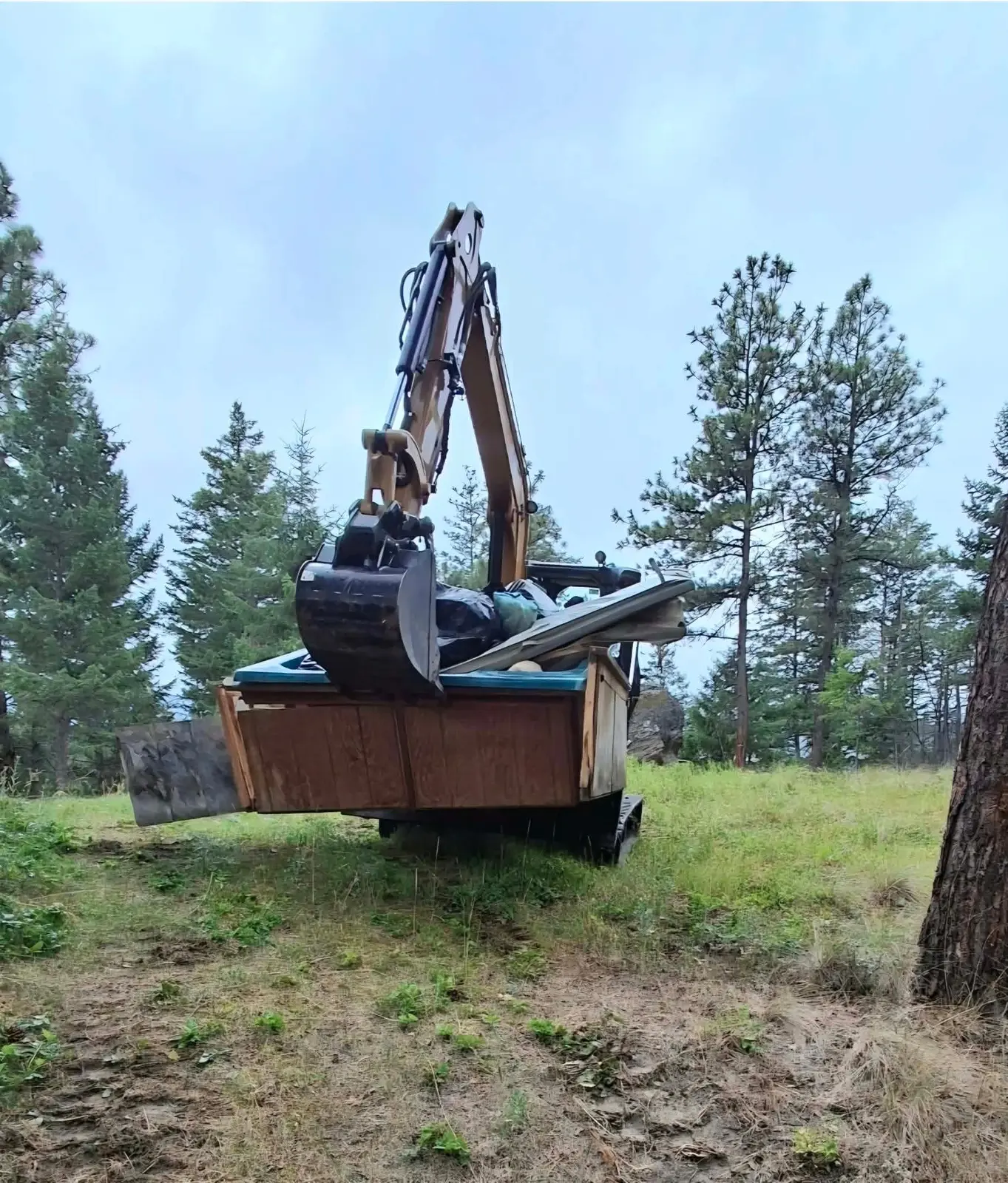 Excavator working on a wooded hillside lot
