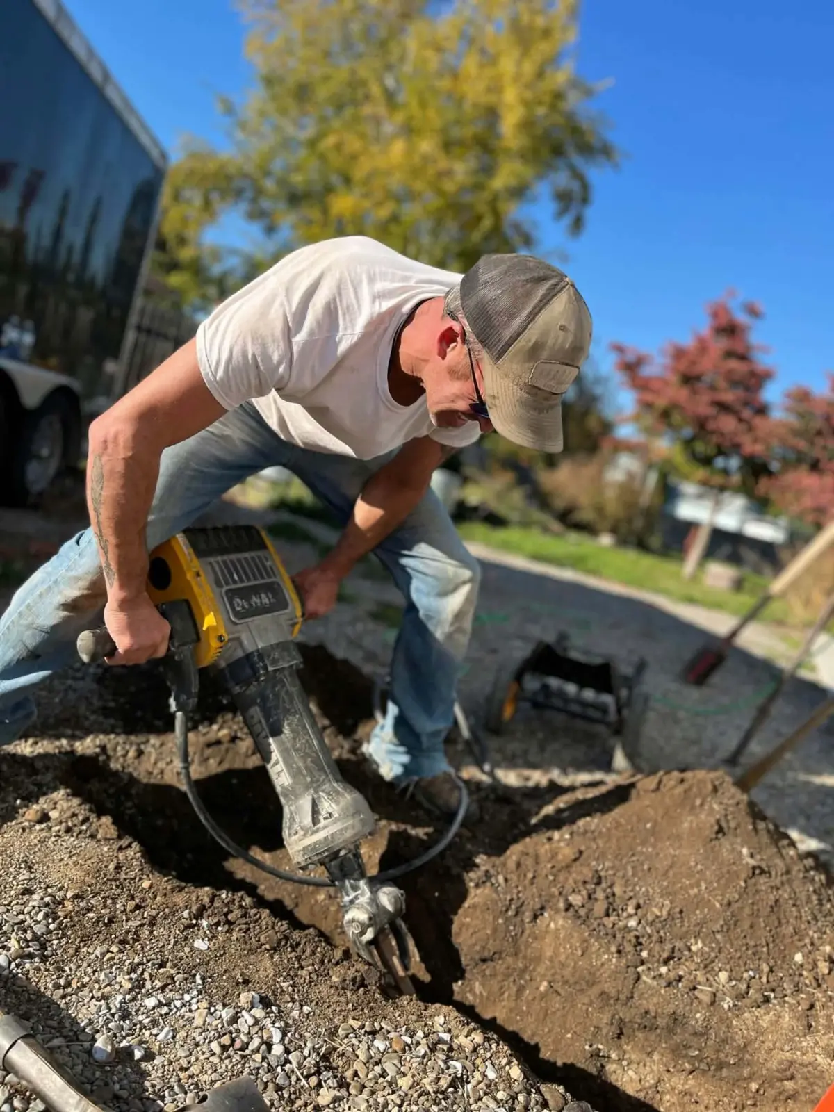 Rustic Ridge crew member using a jackhammer to trench a yard